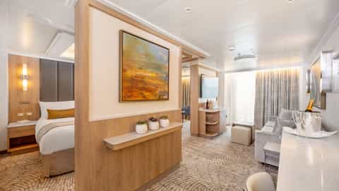 A suite with a bed, seating area, and minibar - Sun Princess, Princess Cruises