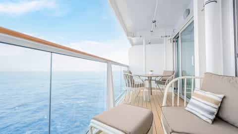 A balcony with seating overlooks the ocean - Sun Princess, Princess Cruises